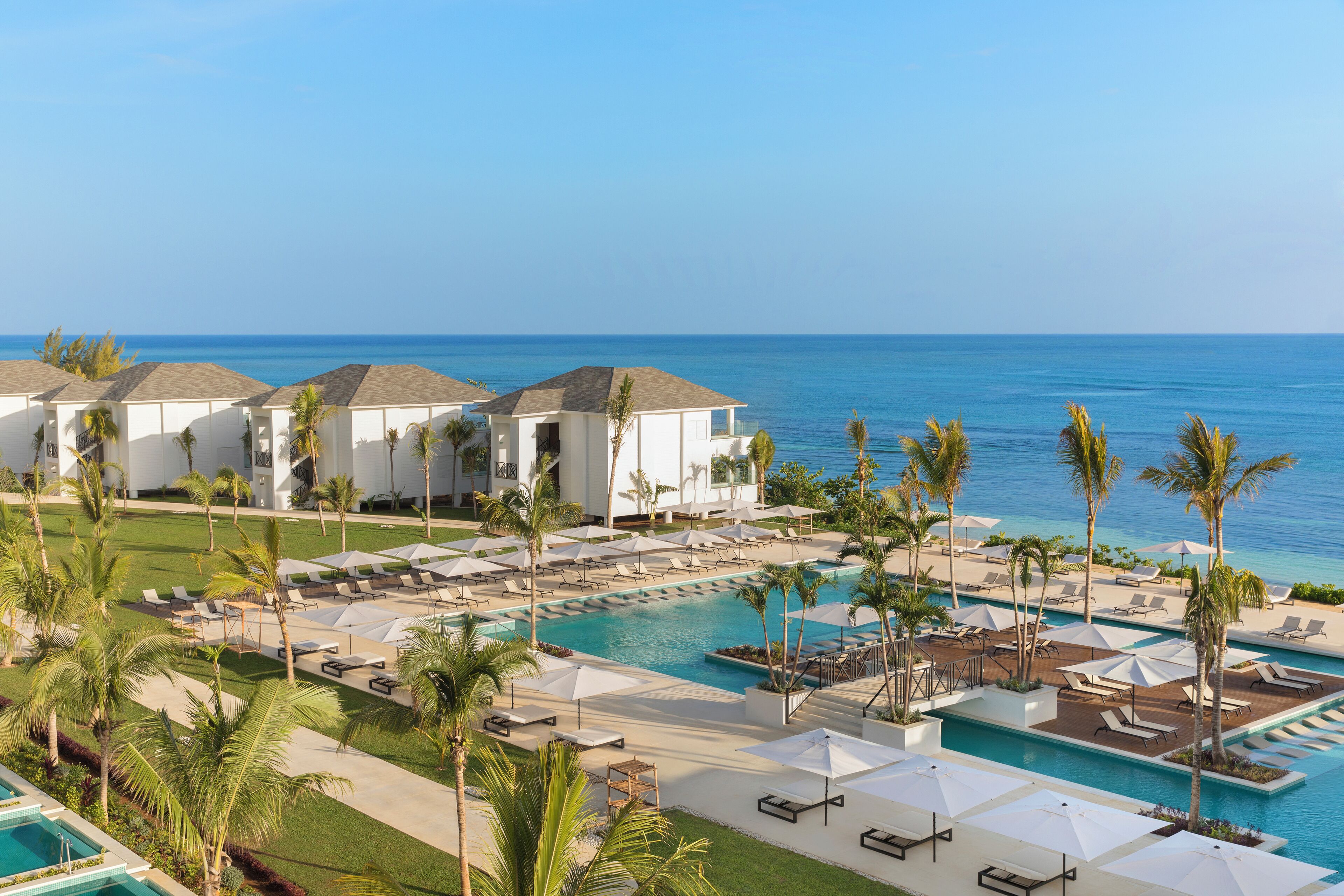 Un resort con piscina, sillas de descanso y palmeras.
