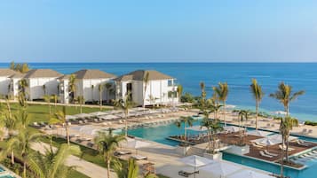Un resort con piscina, sillas de descanso y palmeras.