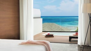 Un dormitorio con un ventanal grande con vista a una playa y al océano.