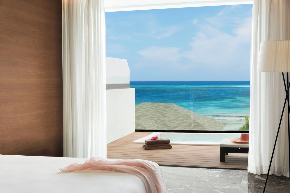 Ein Schlafzimmer mit großem Fenster mit Blick auf Strand und Meer.