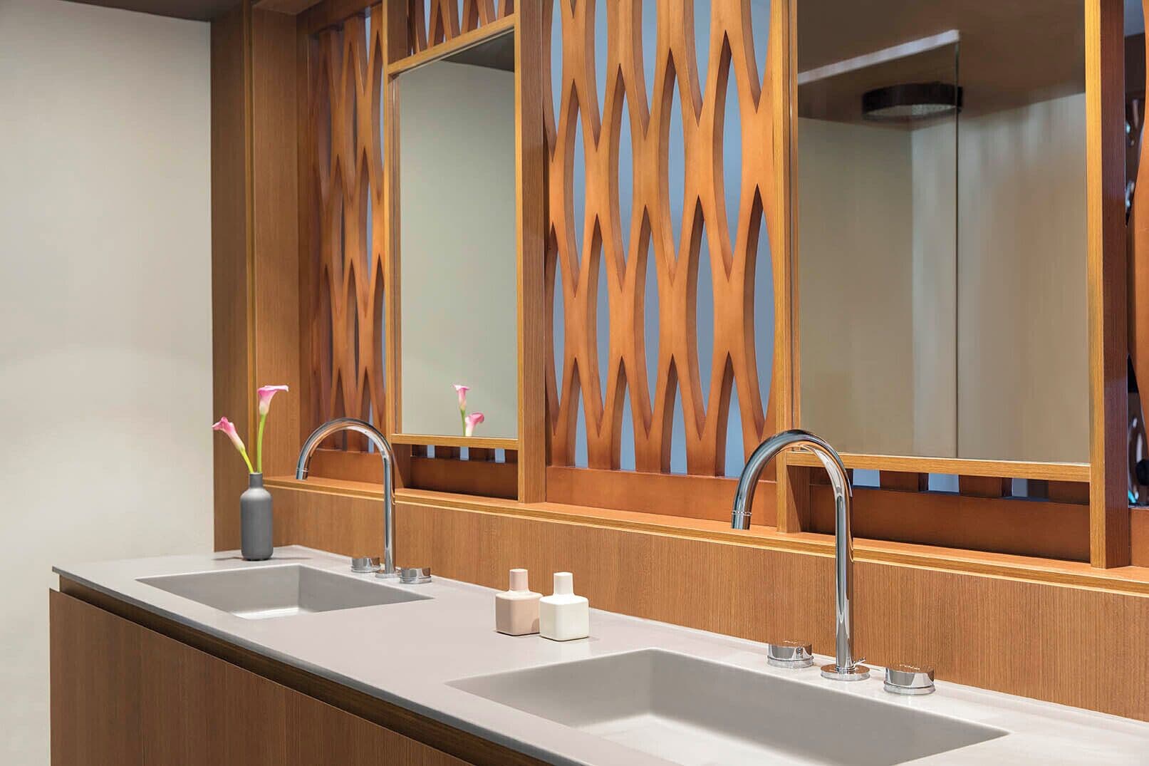A bathroom with a double sink, wooden paneling, and a large mirror.