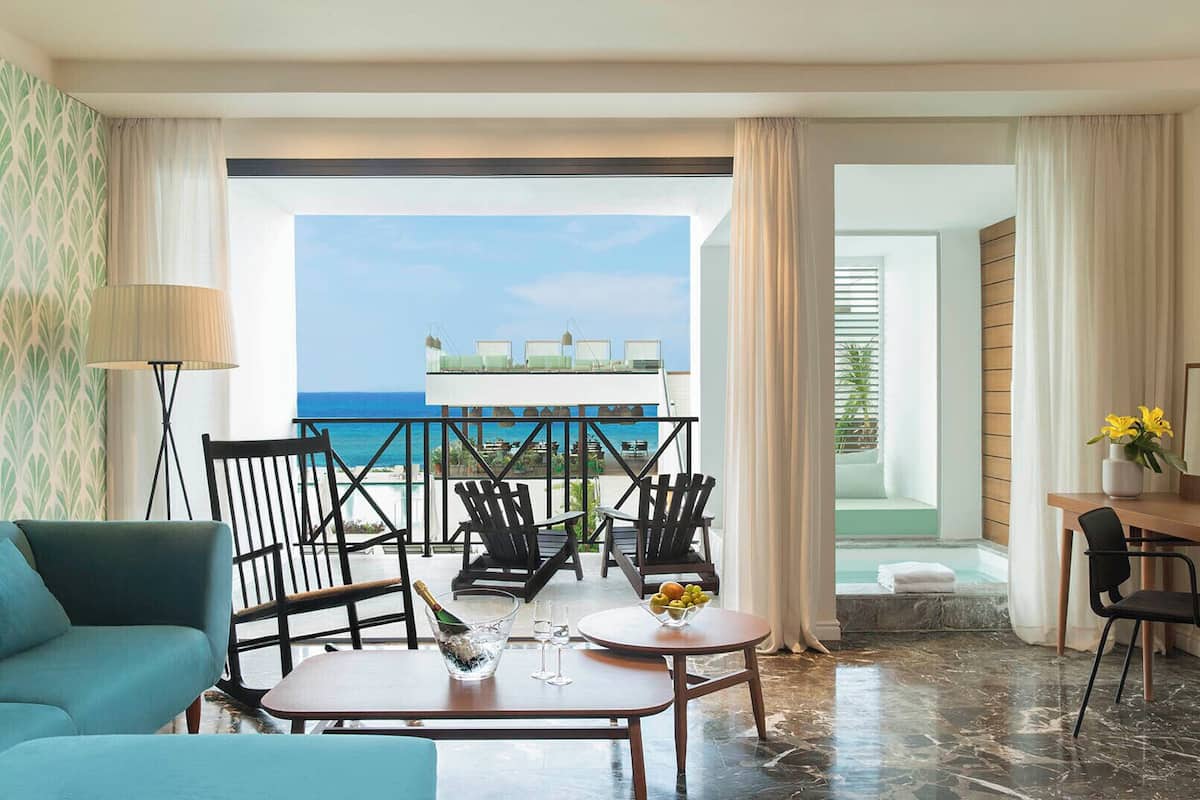 Ein Hotelzimmer mit Balkon, Essbereich und Meerblick.
