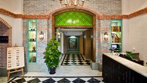 A lobby with a checkered floor, a reception desk, a chandelier, and a green decorative wall.