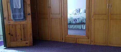 A bedroom with a bed, wooden wardrobe, and a window.