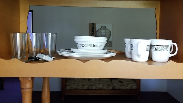 A bunk bed with a small table in the middle. The table has a stack of plates, a few cups, and a bottle of hand sanitizer.