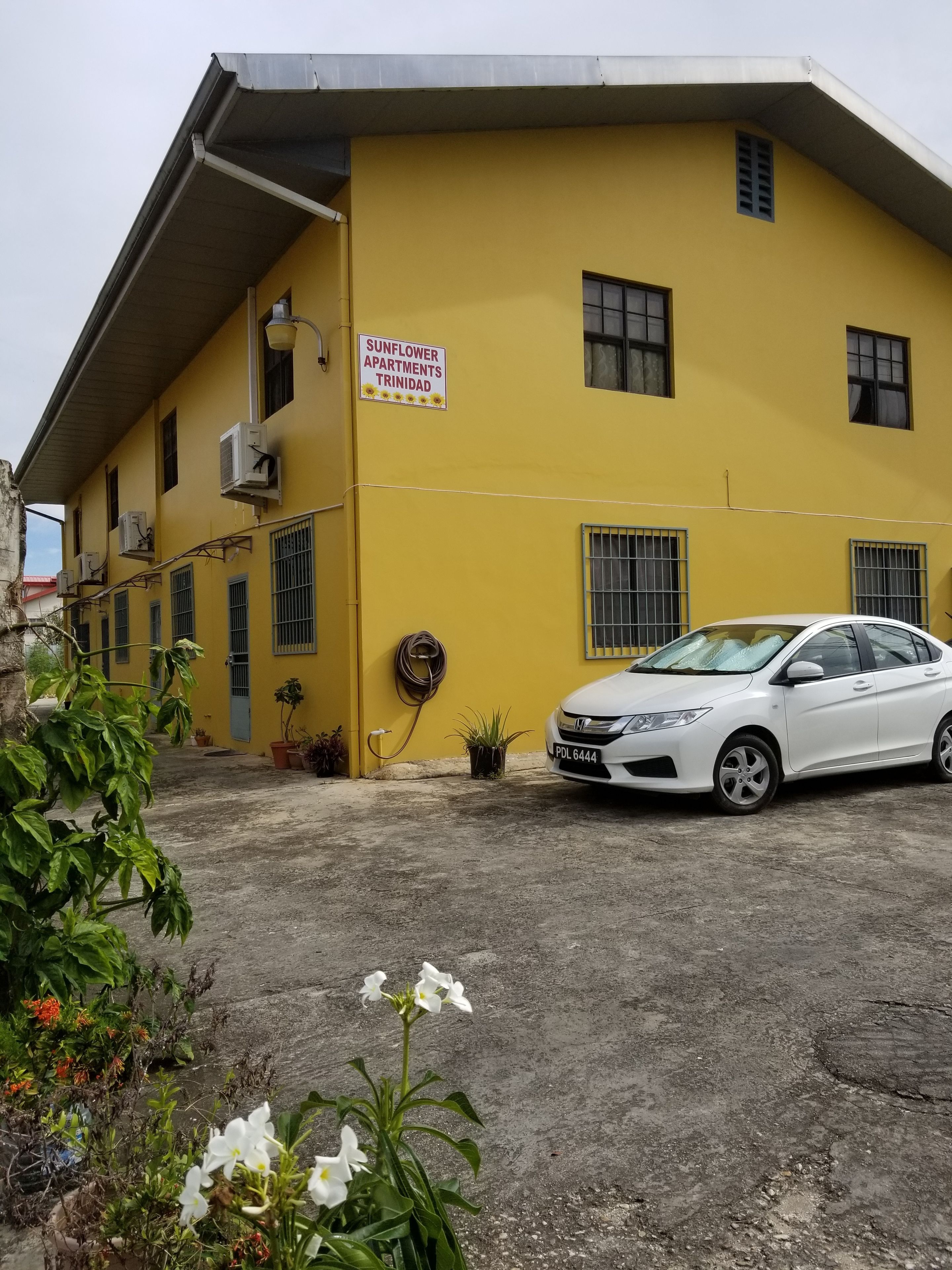A yellow building with a sign reading "Sunflower Apartments Trinidad".