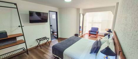 A hotel room with a bed, a TV, a chair, and a small table.
