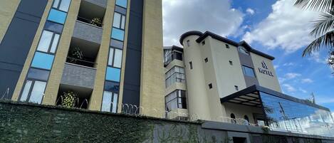 A hotel with a modern design, featuring a mix of glass and brick facades, multiple balconies, and a paved entrance area.