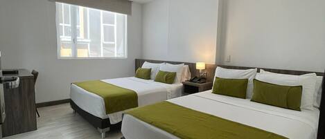 A hotel room with two beds, a desk, and a window.