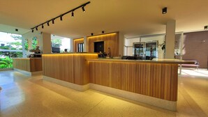 Zona de recepción con un mostrador de madera, una máquina de café y una pantalla de televisión.
