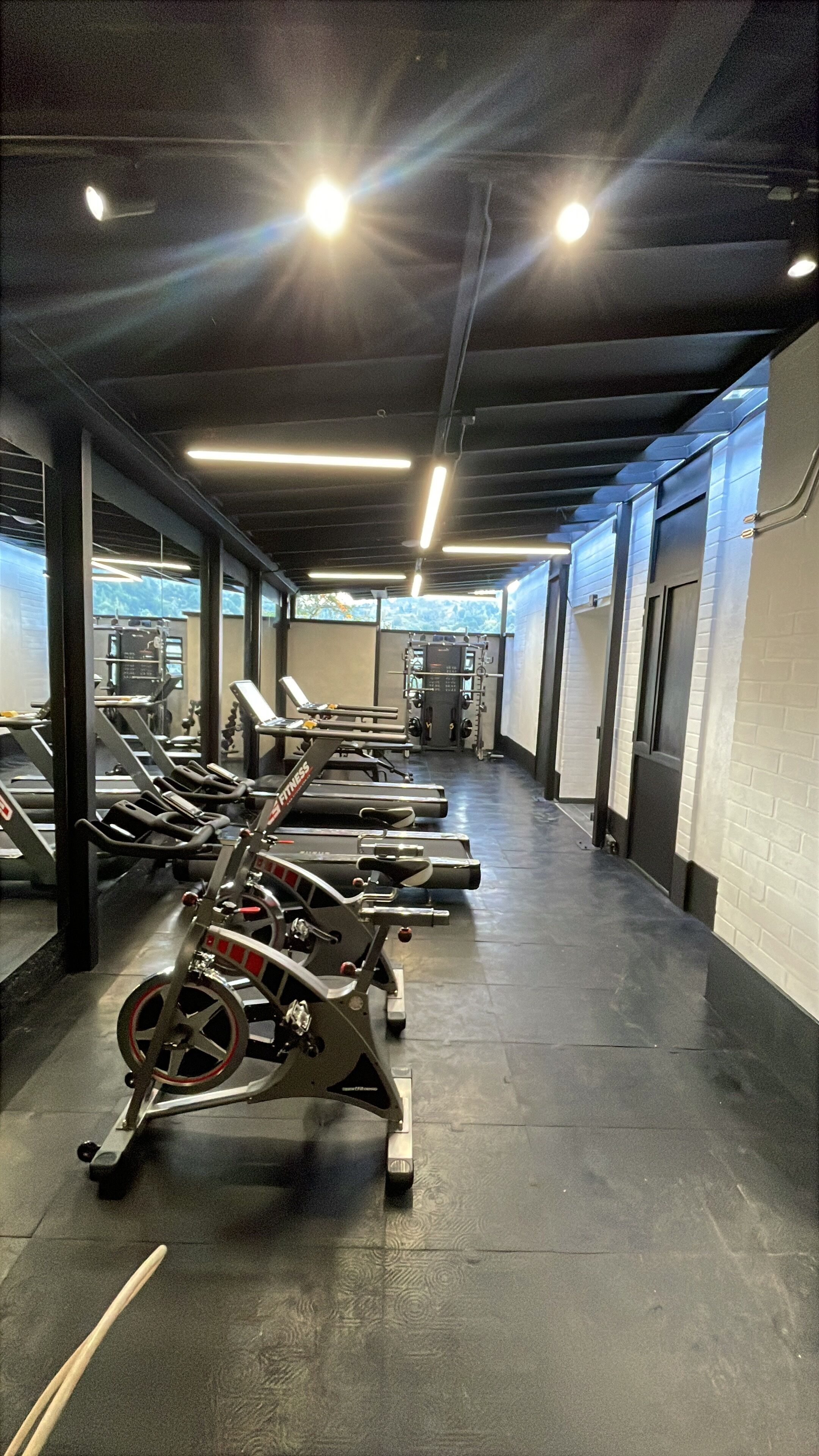 Un gimnasio con cintas de correr, máquinas de pesas y un espejo grande.