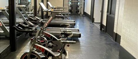 A gym with treadmills, weight machines, and a mirrored wall.