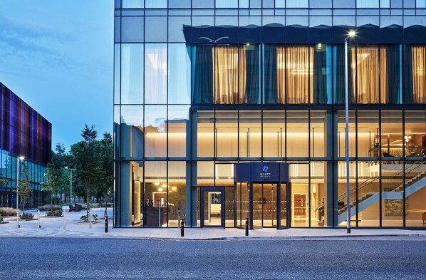A modern hotel with a glass facade, a visible entrance, and a staircase leading to the upper floors.