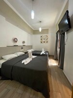 Een hotelkamer met twee bedden, een flatscreen televisie, een wandgemonteerde televisie en een klein tafeltje met telefoon.