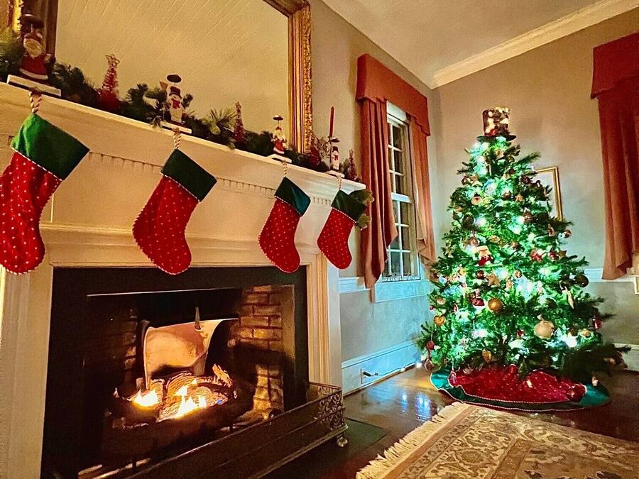 A cozy living room with a fireplace, a Christmas tree, and stockings on the mantel.