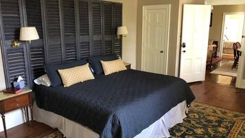 A large bed with a dark quilt, two bedside lamps, and a patterned rug.