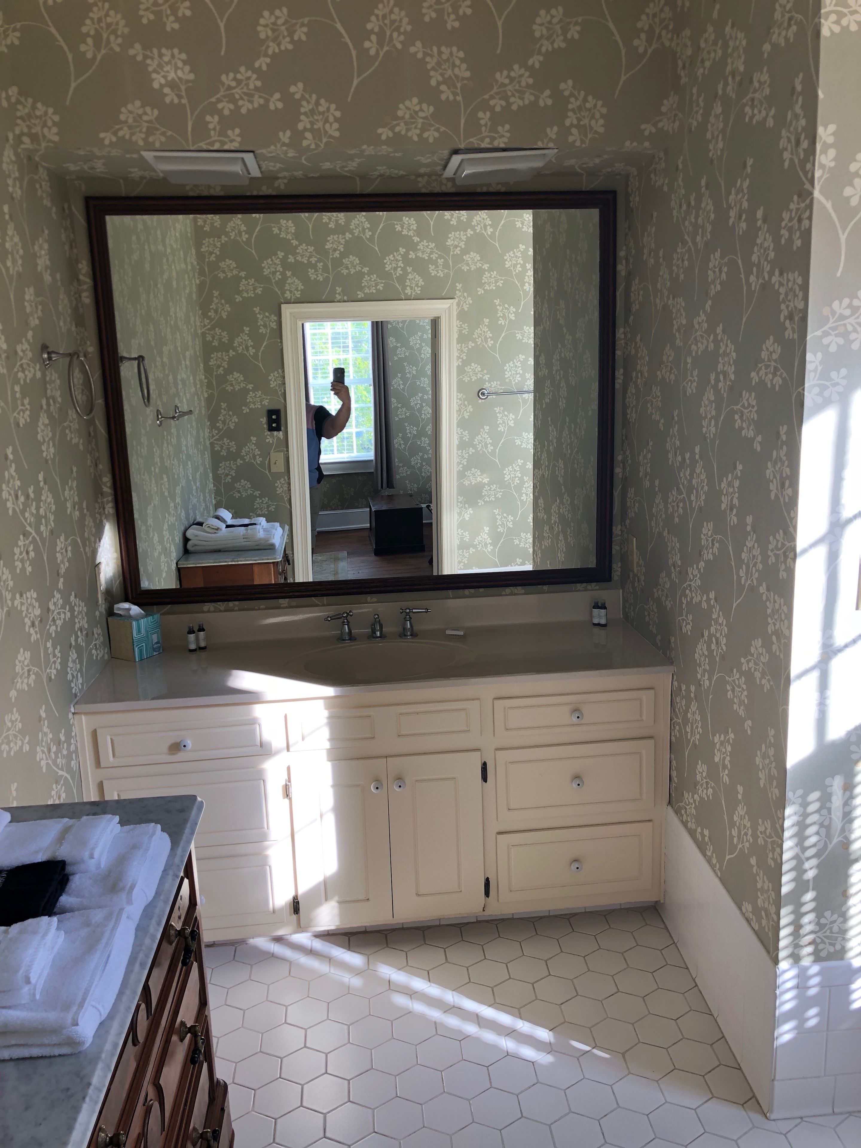 A bathroom with a large mirror, a double sink vanity, and a hexagonal tiled floor.
