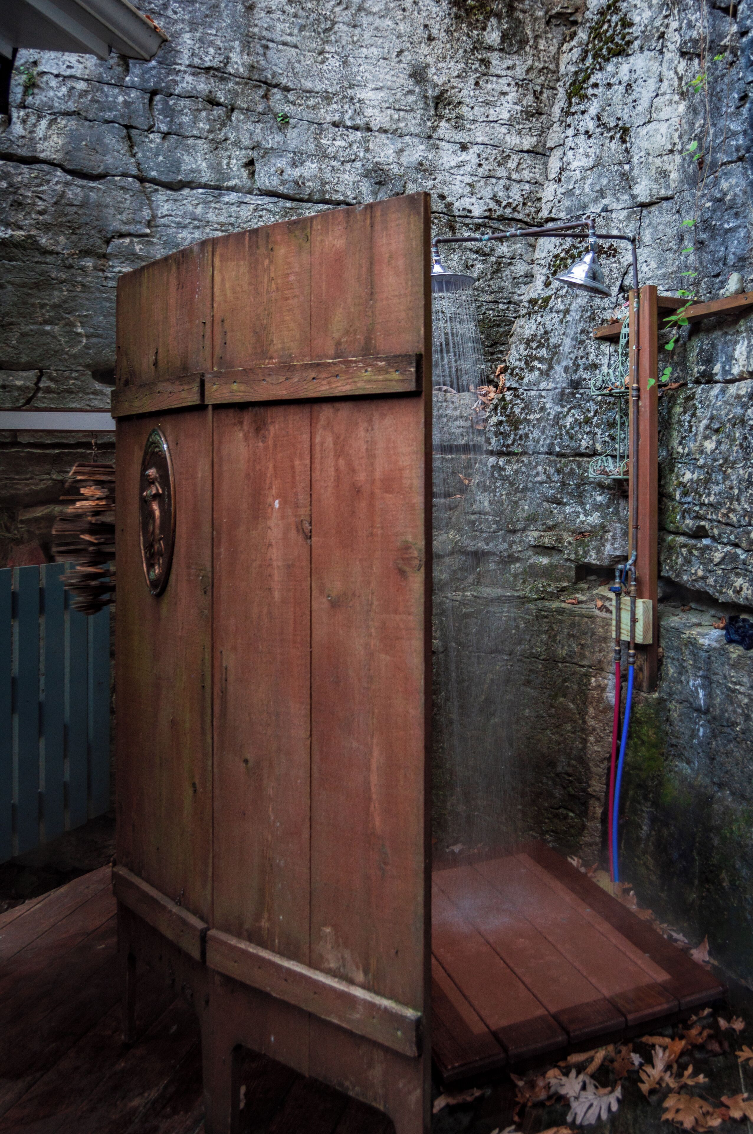 A rustic wooden cabinet with a metal emblem, a stone wall, and a wooden bench.
