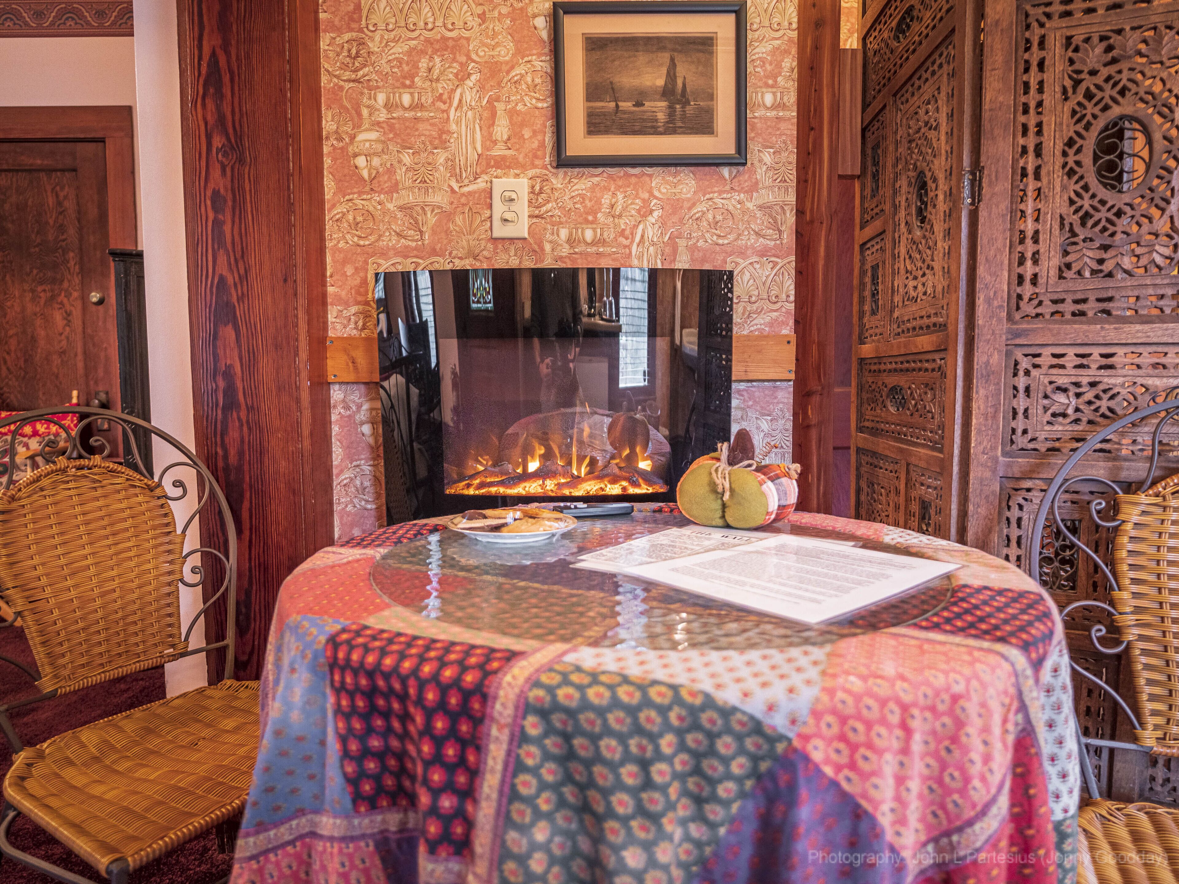A cozy room with a fireplace, wicker chairs, and a table with a placemat.