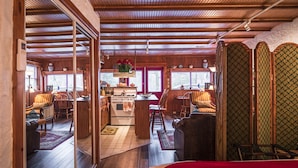Un interior de cabaña acogedor, con vigas de madera, una zona de cocina y un comedor.