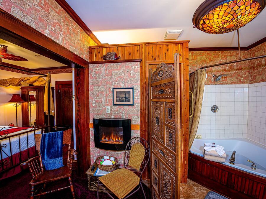 A traditional room with a fireplace, a bathtub, and a wooden chair.