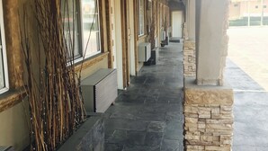 A covered walkway with stone flooring, wooden beams, and windows. - Royala Inn (Montebello)
