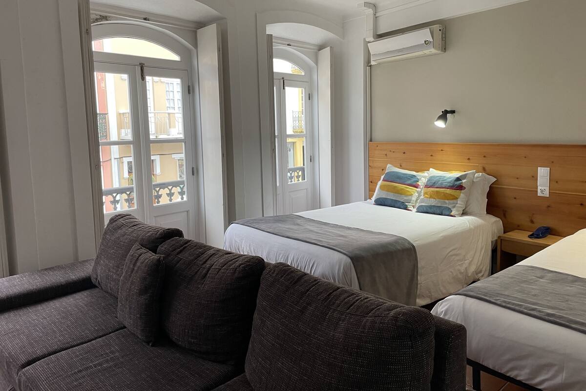 Ein Hotelzimmer mit Bett, einer Couch und zwei Fenstern.
