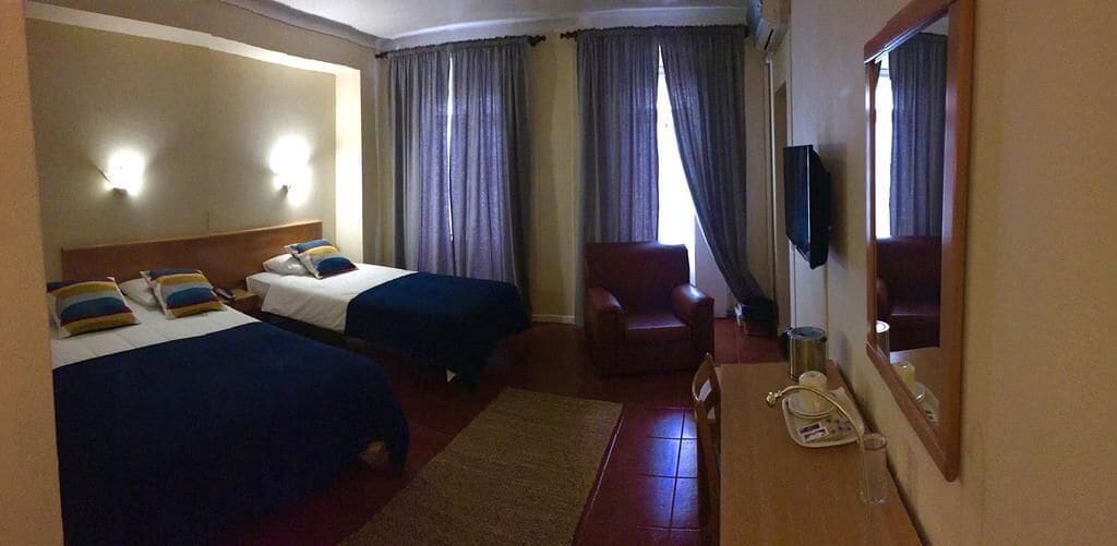 Una habitación de hotel con dos camas, una silla, un escritorio con teléfono y un espejo.