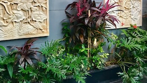A wall with two floral relief panels and a variety of indoor plants. - Villa Legian (Legian)