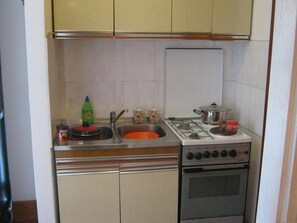 Una cocina compacta con fregadero, estufa y armarios.
