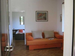 Una habitación con un sofá, un cuadro en la pared y una puerta que da a otra estancia.