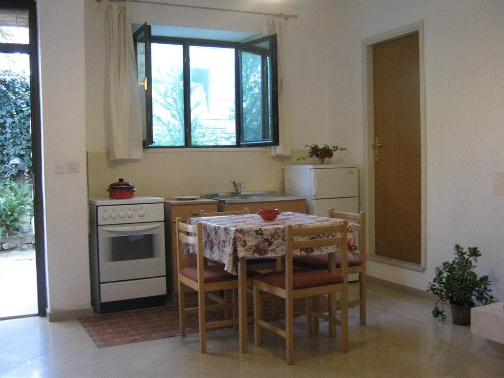 A compact kitchen with a dining table, chairs, a refrigerator, and an oven.