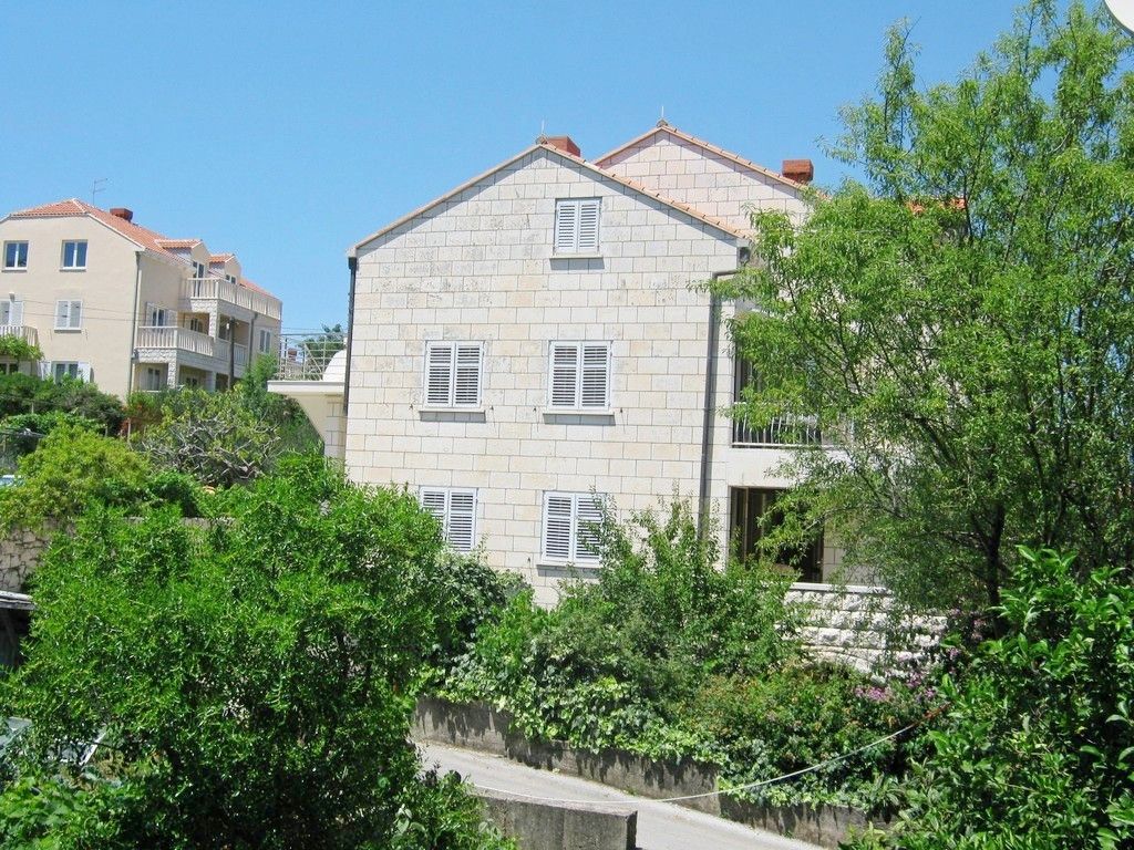A multi-story building with a stone facade, white shutters, and a balcony.