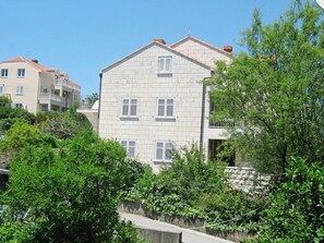 A multi-story building with a stone facade, white shutters, and a balcony. - Apartments Ivica (Dubrovnik)
