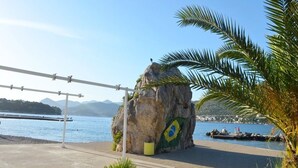 Ein Felsen mit der brasilianischen Flagge, einem klaren Himmel und einem Gewässer.