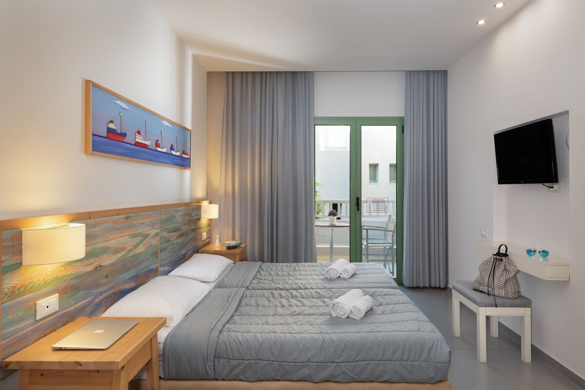 Une chambre d’hôtel avec un lit, un bureau, une télévision et un tableau au mur.