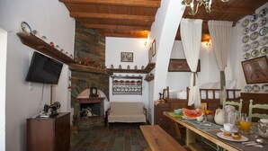 Un comedor acogedor con una mesa de madera dispuesta para el desayuno, una chimenea de piedra y un televisor montado en la pared.