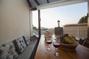 Enjoy a seaside dining experience on this tranquil outdoor terrace with a table set for two, complete with a wicker basket and wine glasses.