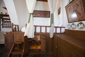 Cozy room with a bench, play area, and decorative plates on the wall, featuring a framed picture and a sloped ceiling.