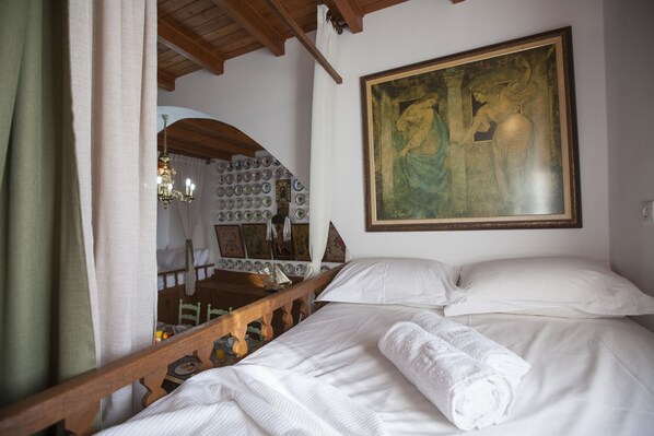 Classic hotel room with a neatly made bed, wooden headboard, and a large framed painting above.