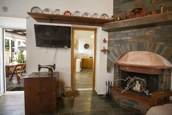 A living room with a stone fireplace, a television mounted on the wall, and a wooden cabinet.