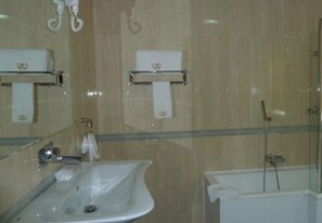 Une salle de bain équipée d’un lavabo, d’un miroir, d’un porte-serviettes et d’une douche.