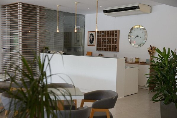 A modern kitchen with a central island, a dining area with a glass table, and a large window with blinds. - Roda Oasis (RODA BEACH - CORFU)