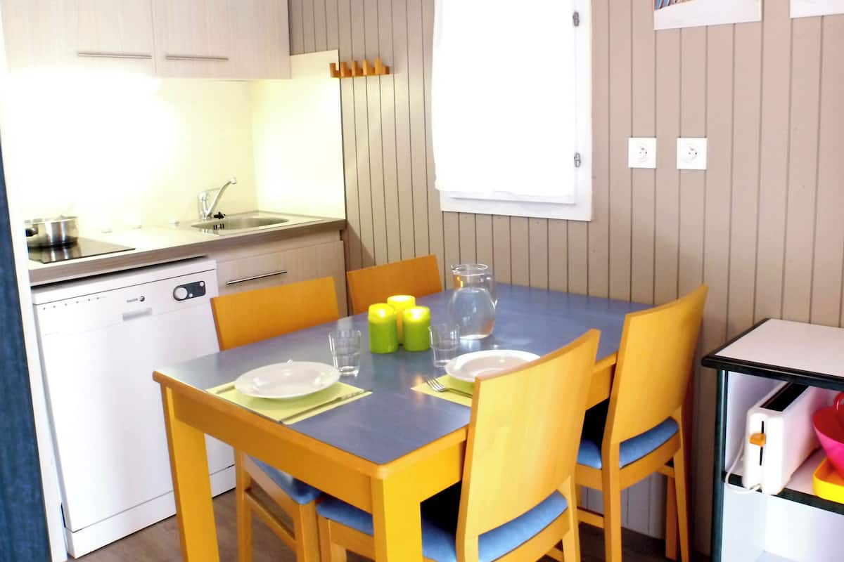 Eine kleine Küche mit Esstisch, Stühlen und einem kleinen Kühlschrank.