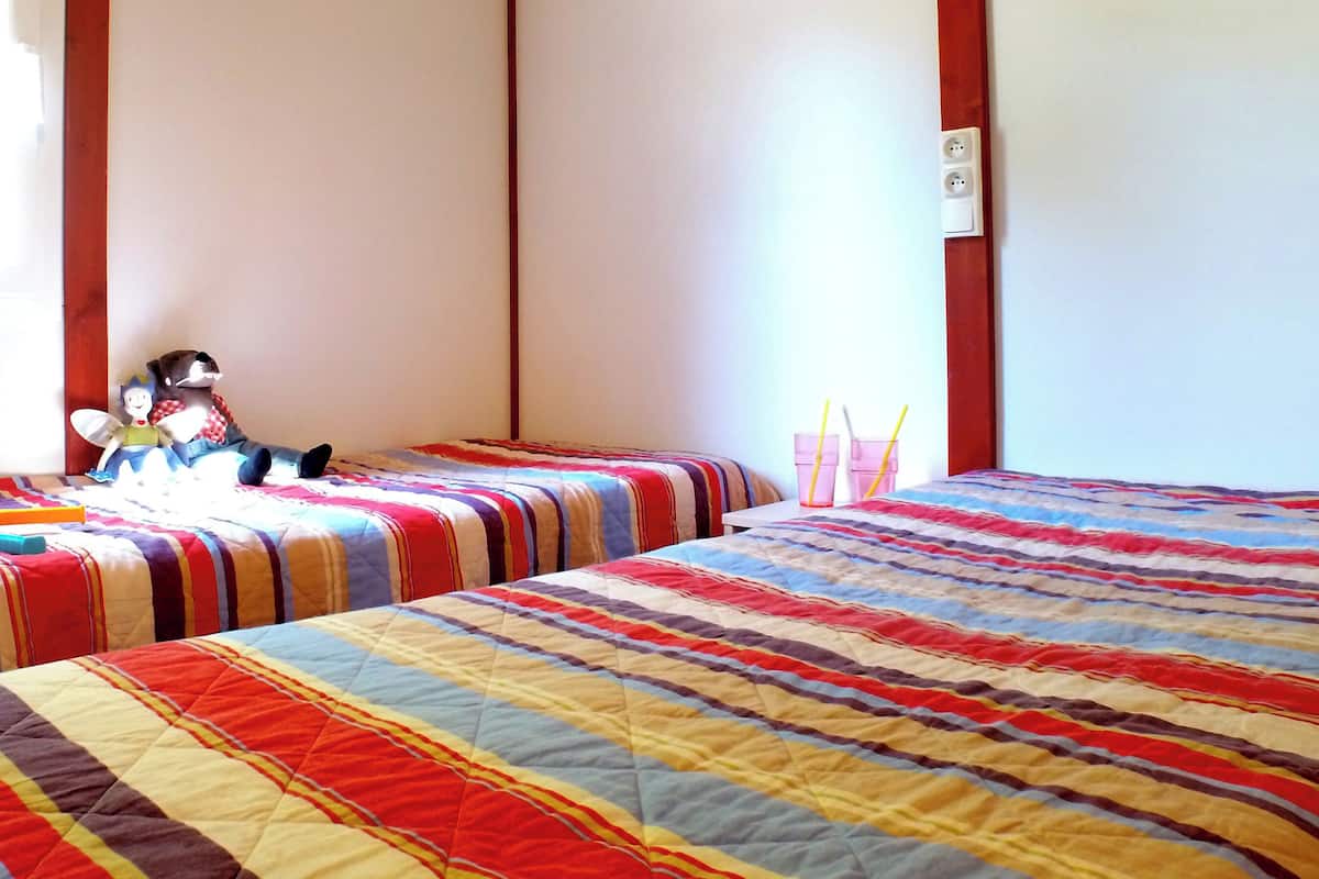 Ein Schlafzimmer mit zwei Betten, gestreifter Bettwäsche, einem Nachttisch, einer Lampe und einem Stofftier.