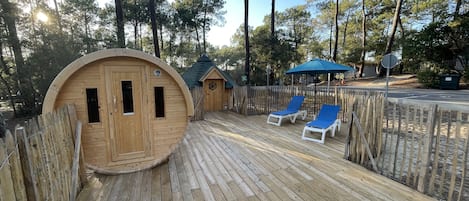 A wooden deck with lounge chairs and a small wooden structure.