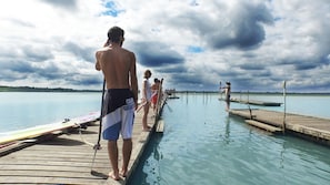 A wooden pier extending into calm water with people standing at the end. - VVF Landes Moliets (Moliets-et-Maa)