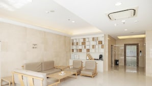 A modern lobby with a sofa, chairs, a coffee table, and a reception desk. - Ji Hotel (Xi'an)