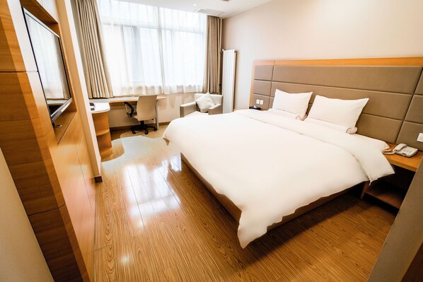 A hotel room with a large bed, a desk with a chair, a TV, and a window with curtains. - Ji Hotel (Xi'an)