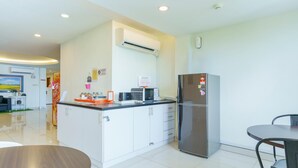 Una cocina moderna con armarios blancos, un refrigerador de acero inoxidable, un microondas y un lavaplatos.